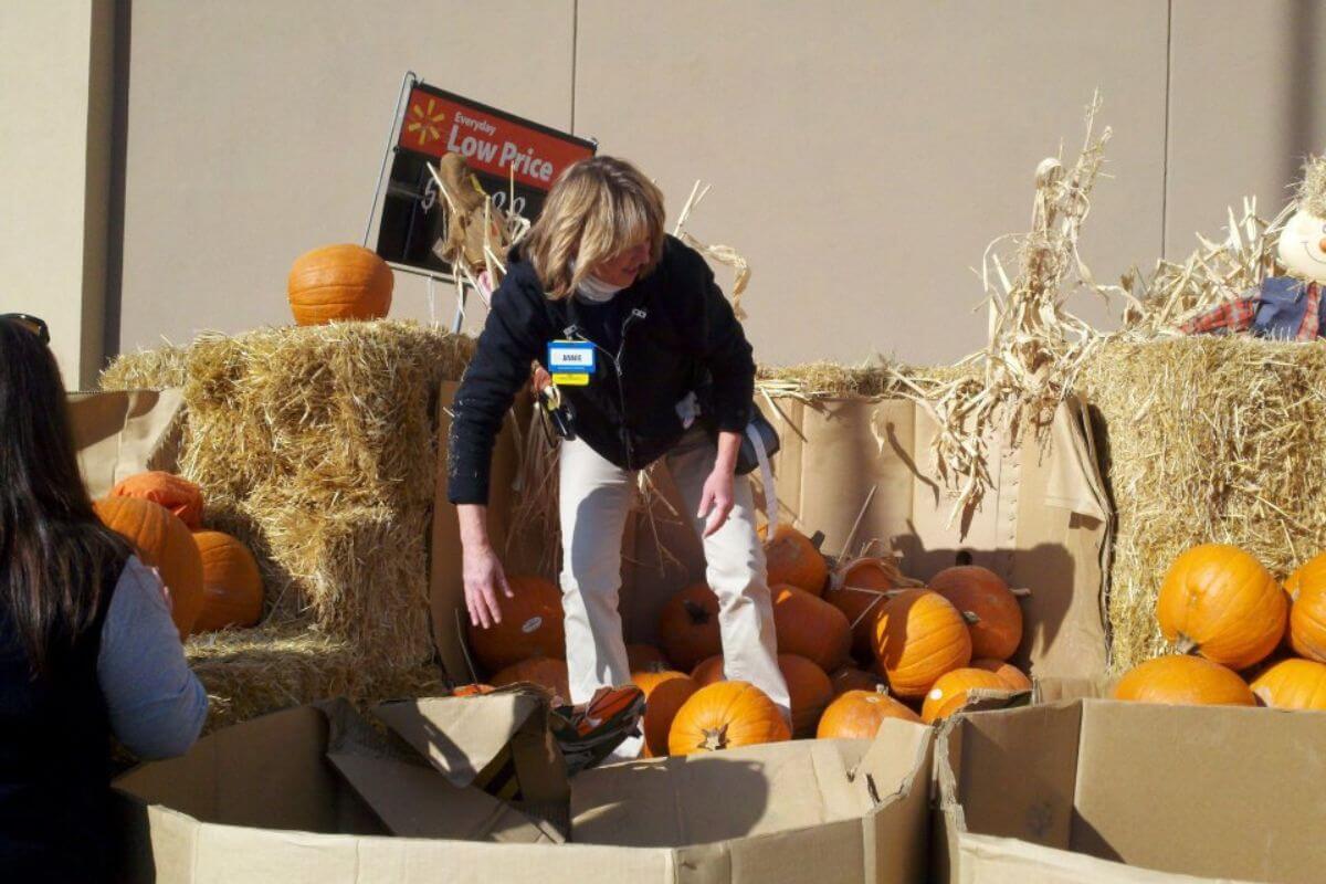 A woman uses pumpkins to decorate an exhibit at a ZooMontana event.