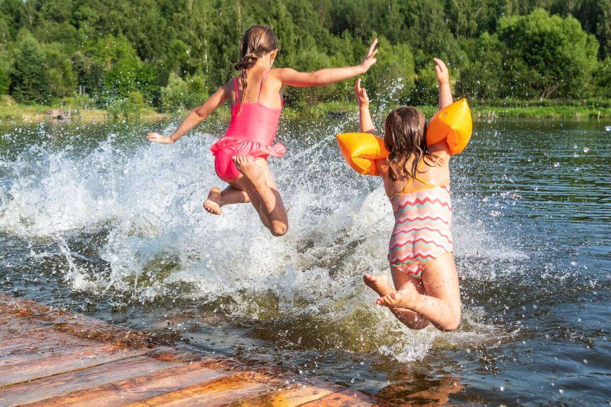 Two girls jump excitedly in the natural spring pool of Gigantic Warm Springs.