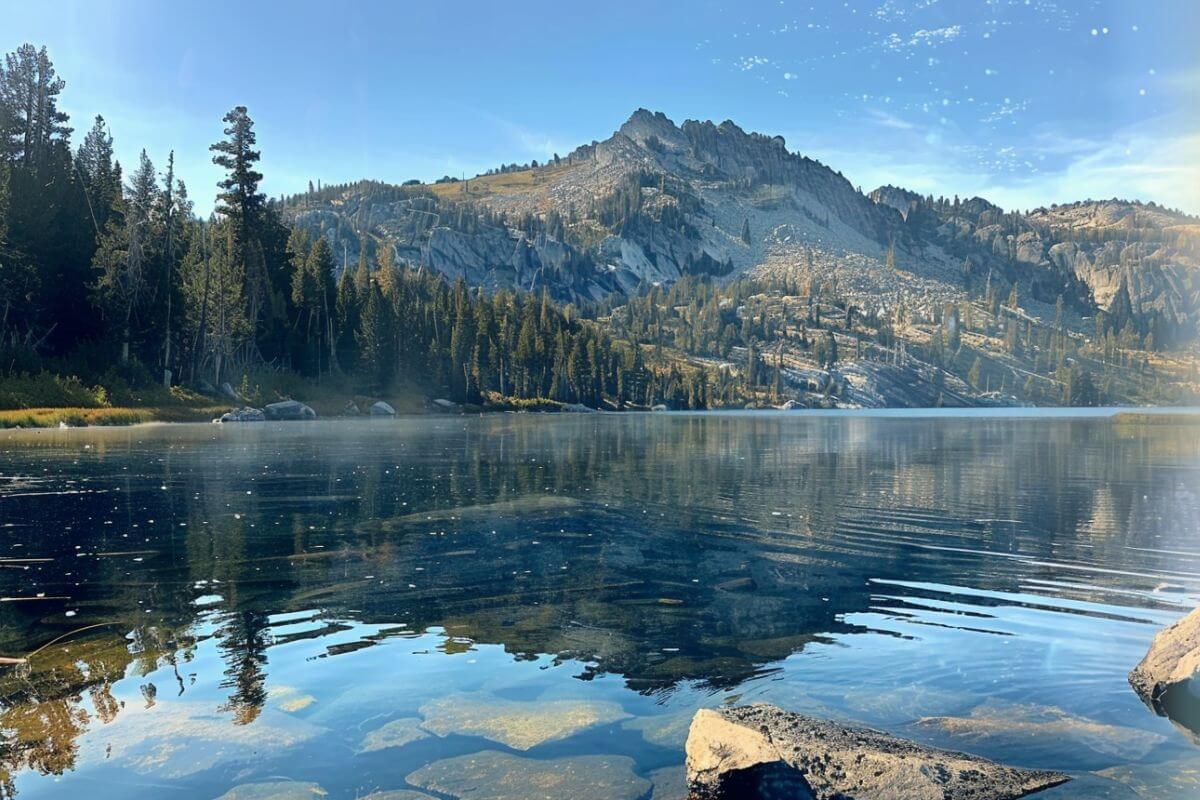 Lake Mary's calm water reflects tall pines and rocky slopes. 