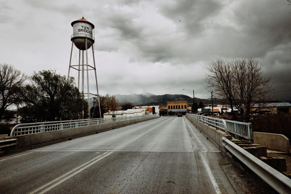 A road with a water tower under a cloudy sky in Montana