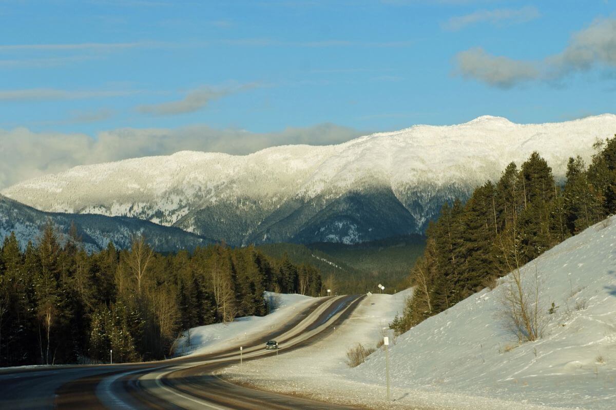A road with snow covered mountains in the background in Montana.