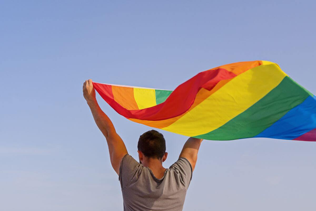 A man holding up a rainbow flag