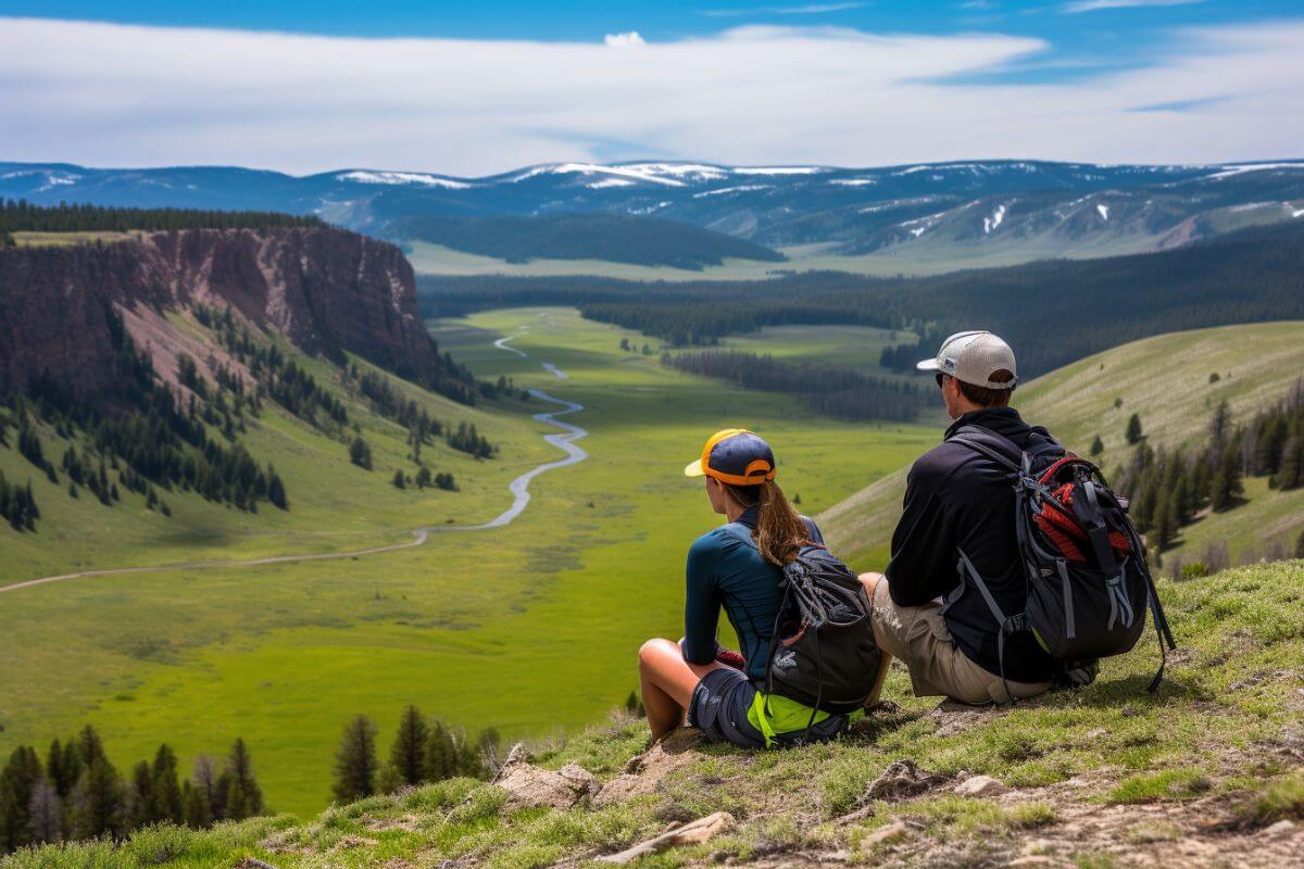 Two people sitting on a hill in Montana overlooking a valley.