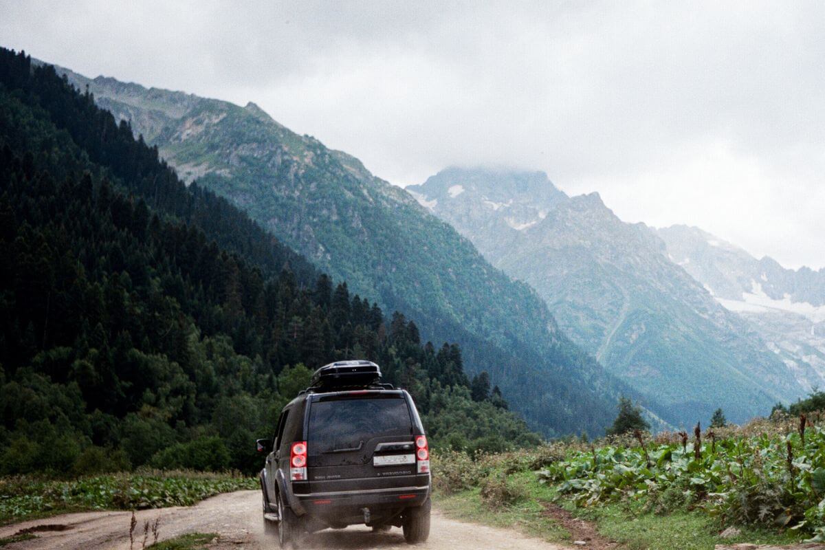 A van drives down a dirt road in the mountains in Montana.