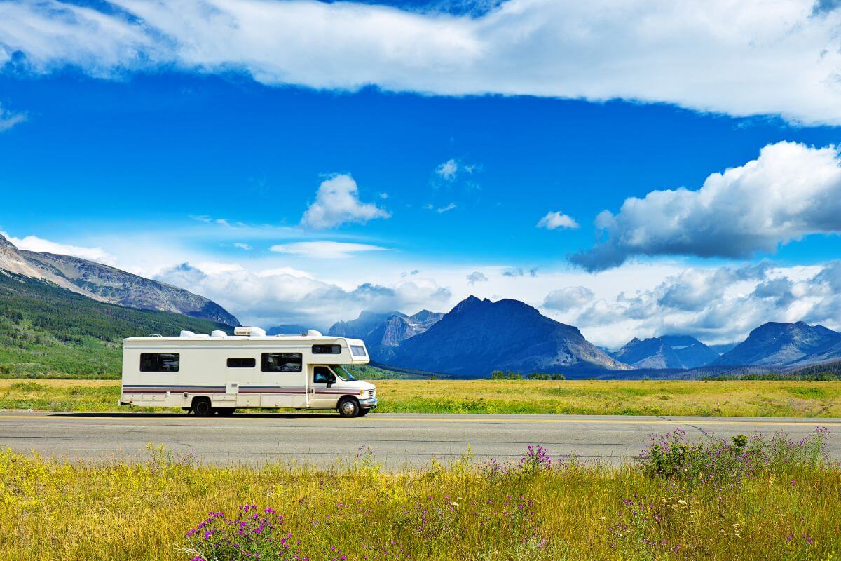 A white RV on a road with mountains in the background in Montana.