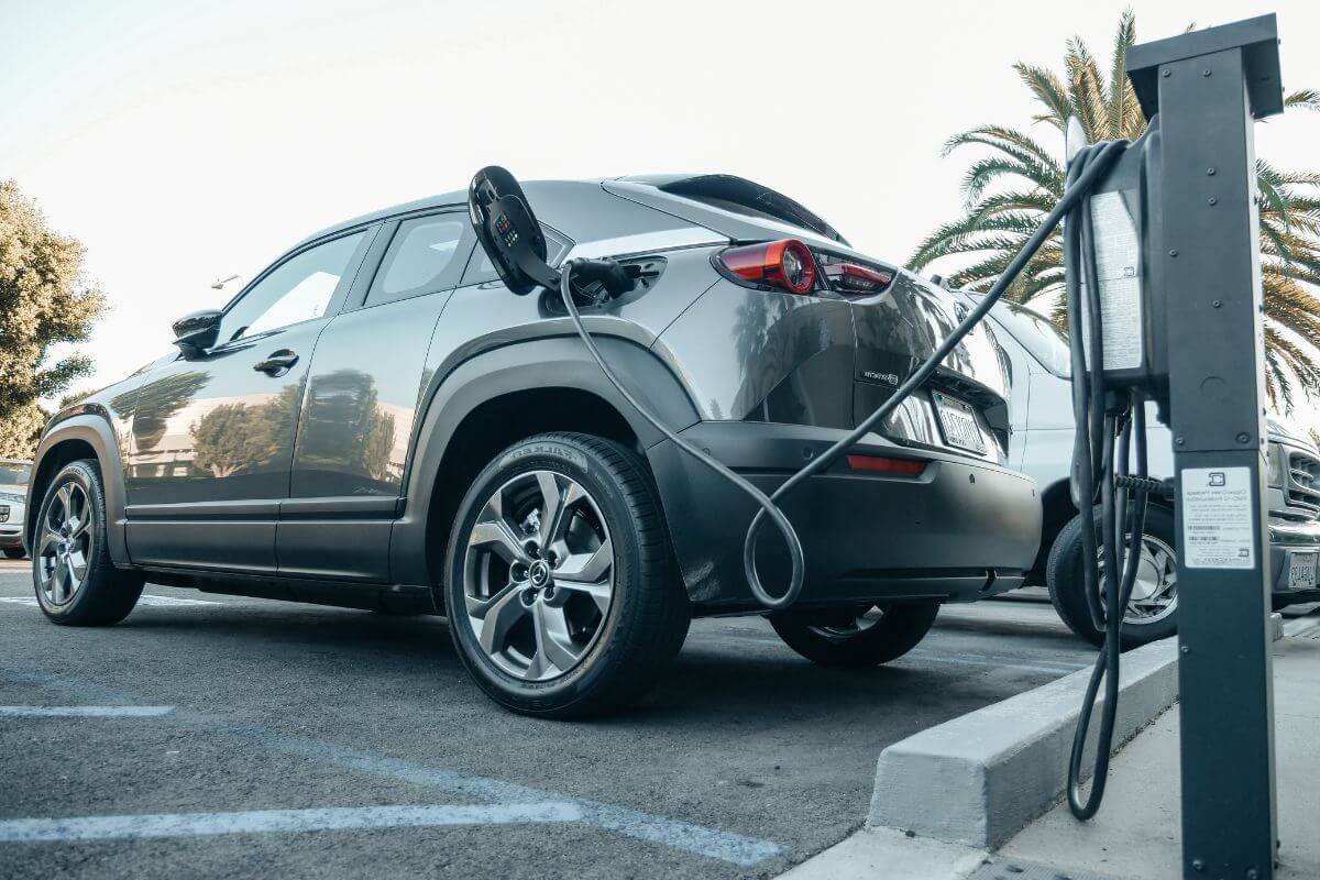 A gray electric car is plugged into an electric charger.