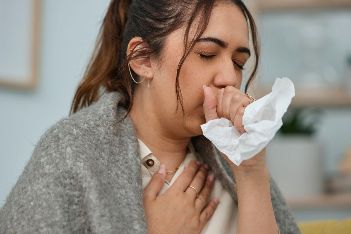 A woman coughing with a tissue.
