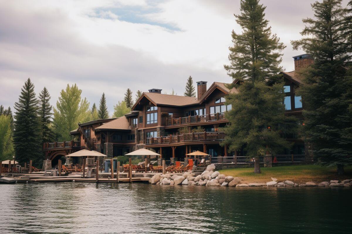A large log cabin sits on the shore of a lake.