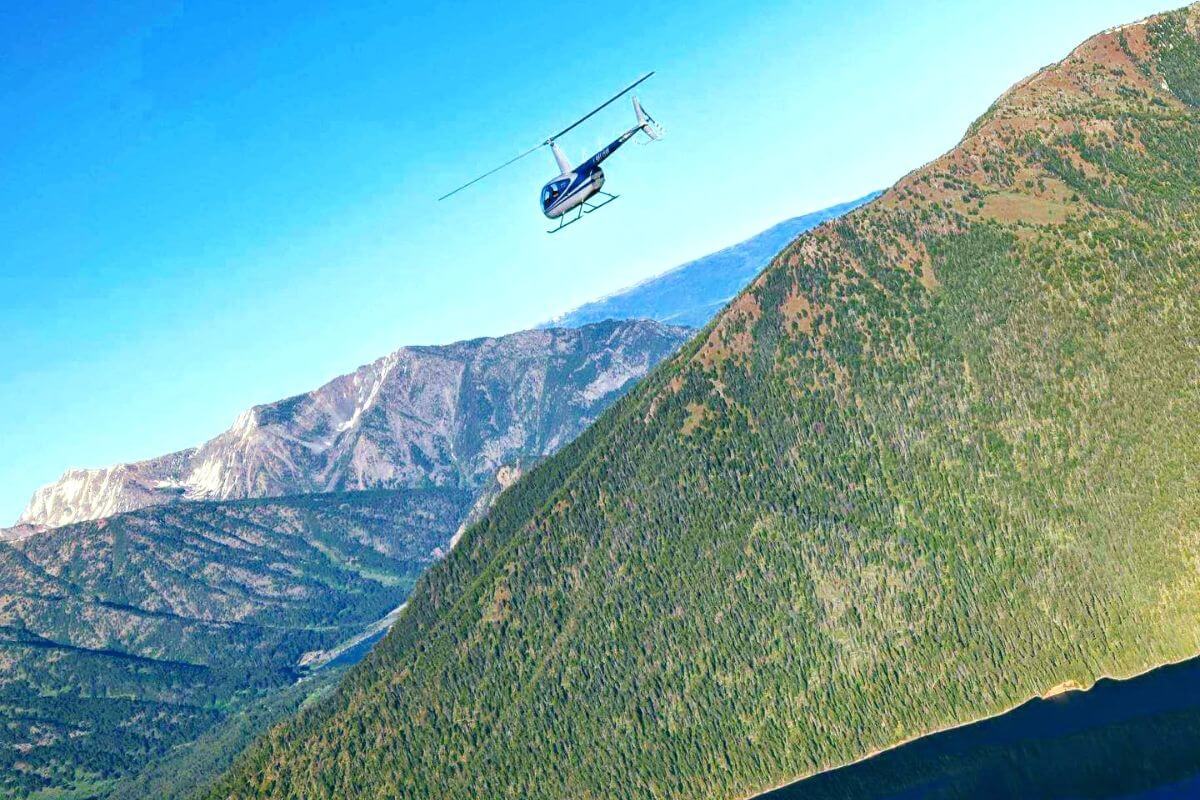 A helicopter from Yellowstone Helicopters flies over a mountain range during one of their Montana helicopter tours.