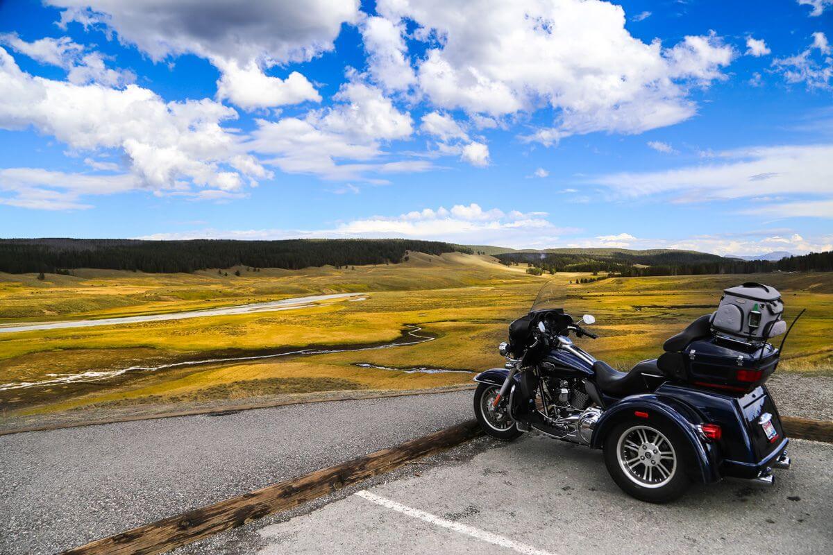 A trike parked on a winding road with open fields at Yellowstone National Park, a top spot for Montana motorcycle tours.