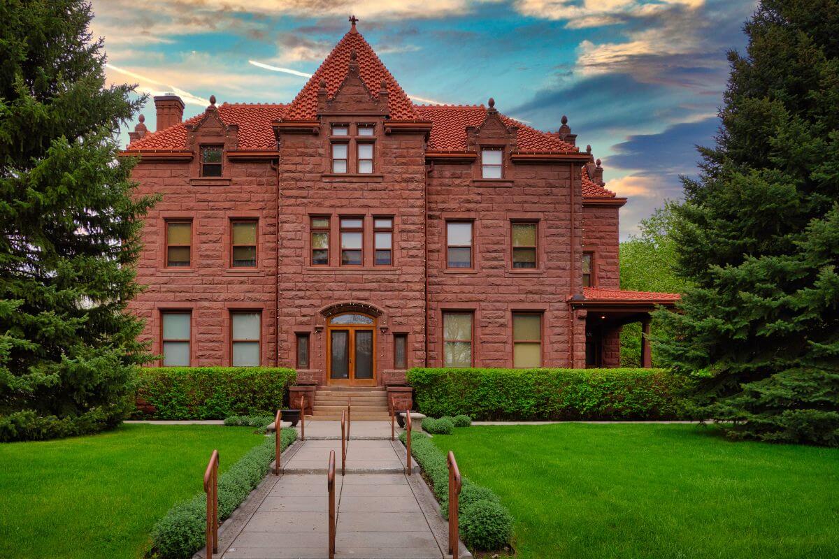 Moss Mansion Museum, a red brick house with a manicured green lawn and trees, in Montana.