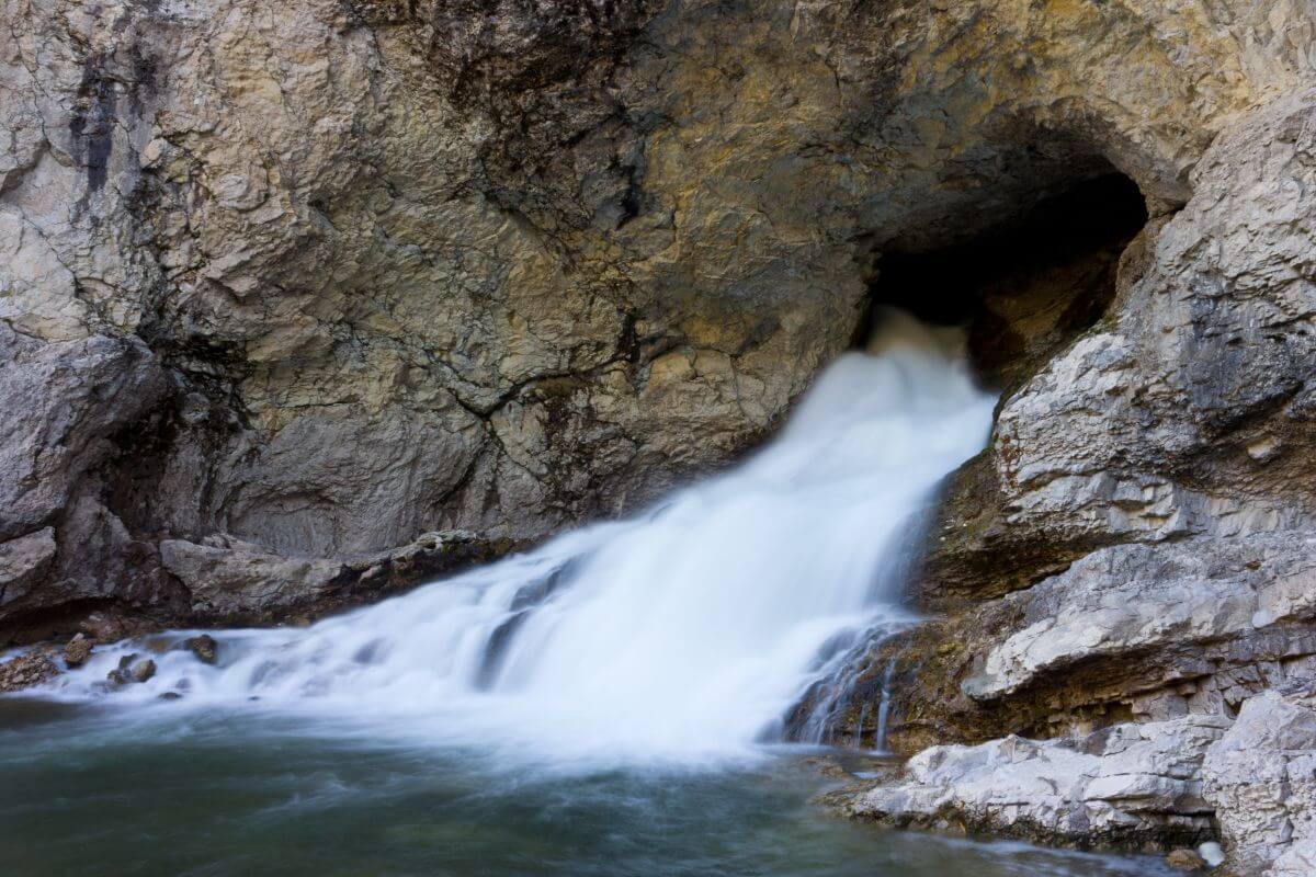 Water flows impressively from the Natural Bridge Falls through a rock formation.