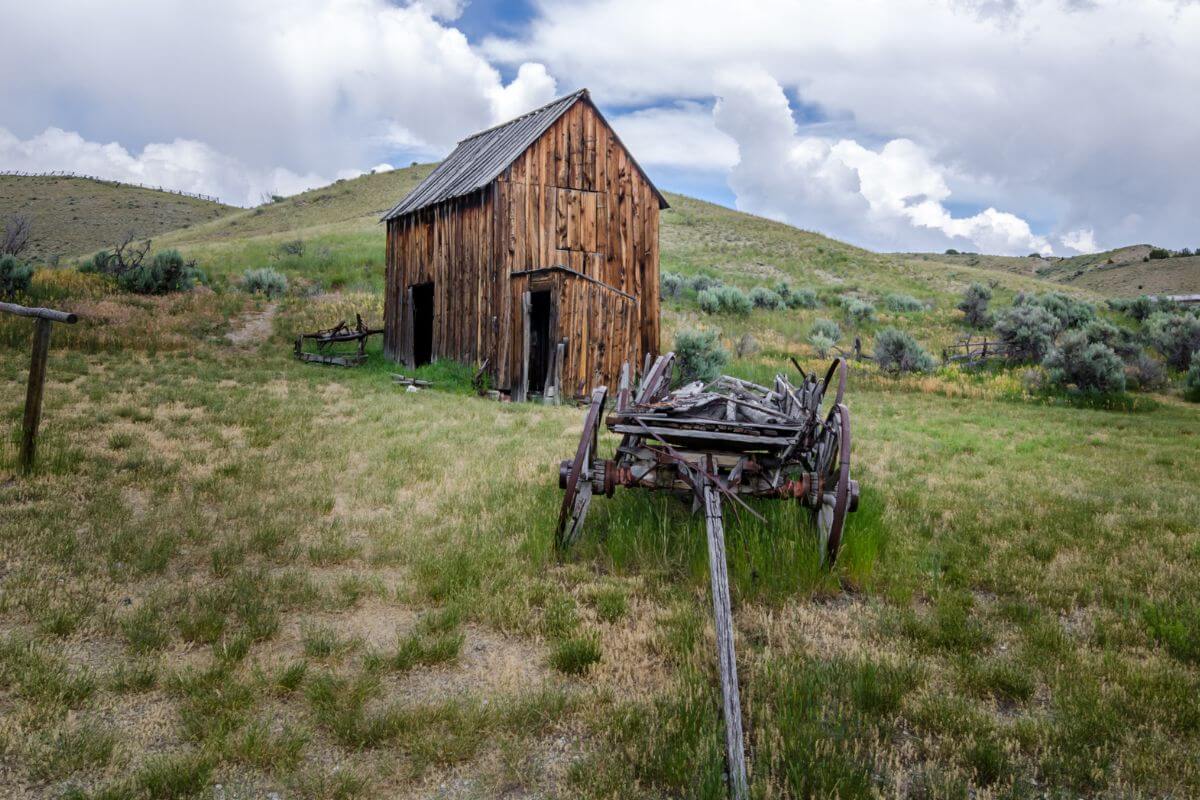 A Dilapidated Barn and Old Wooden Wagon in a Grassy Field in Montana