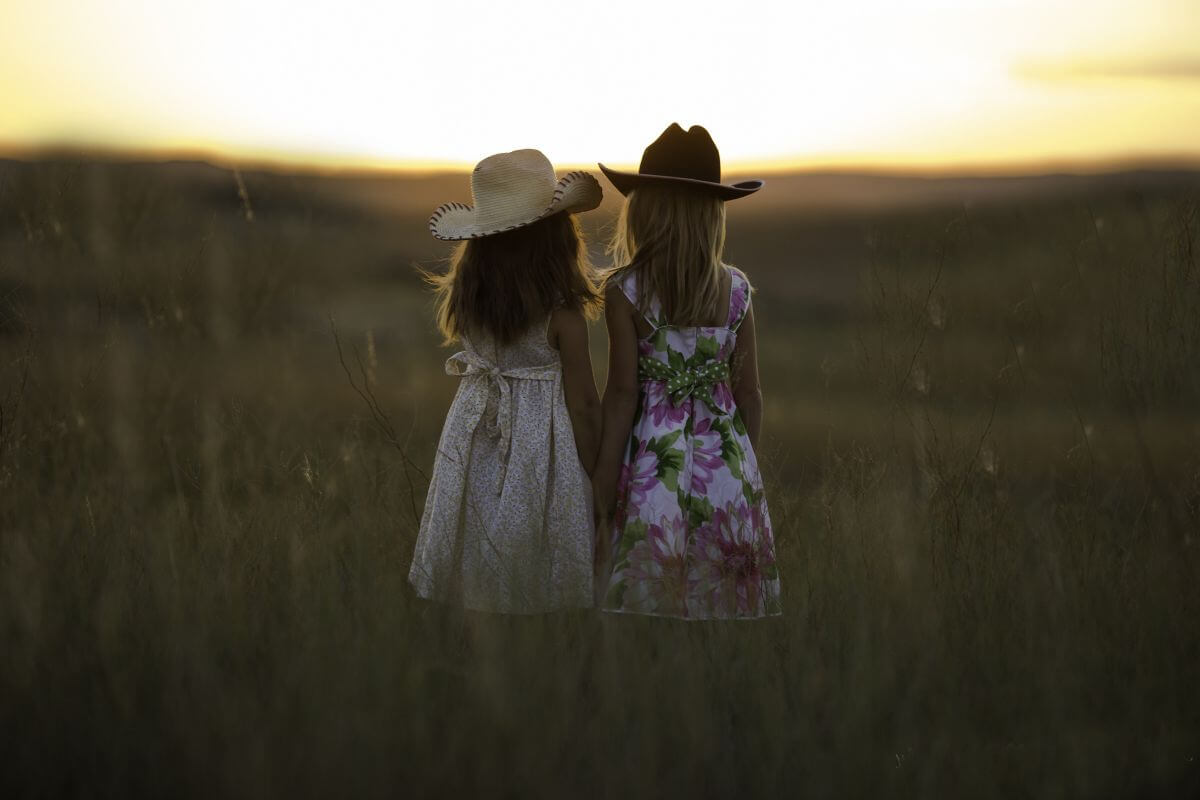 Two girls in dresses standing in a field in Montana.