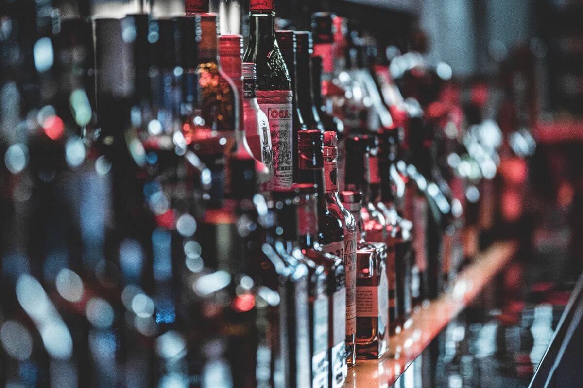Many bottles of liquor are lined up on a bar