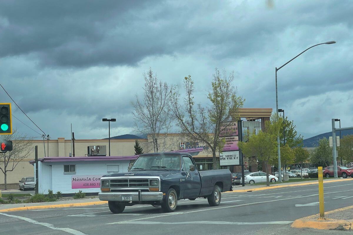 A blue truck driving down a street in Montana.