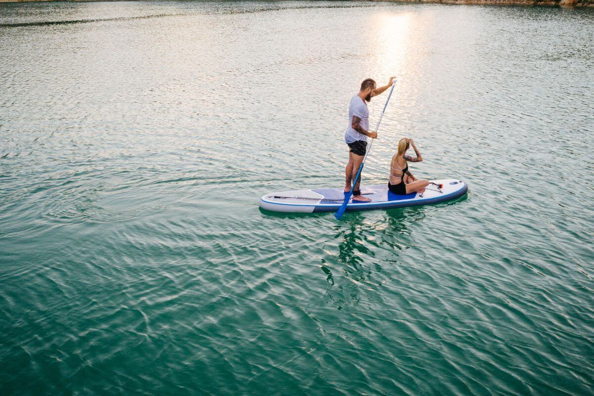 Two people paddleboarding peacefully on a tranquil lake near Martin Waterfall in Montana.