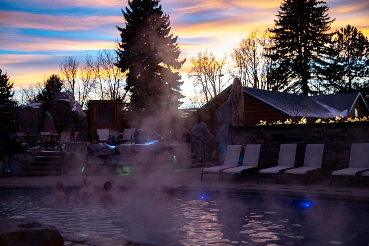 A group relaxes in a hot spring pool at Bozeman Hot Springs during the golden hour.