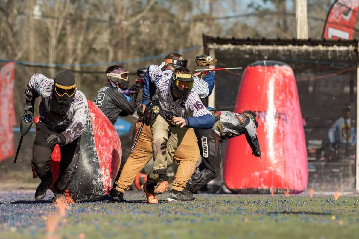 A group of people engage in paintball battle on a field in Diamond Paintball in Montana.
