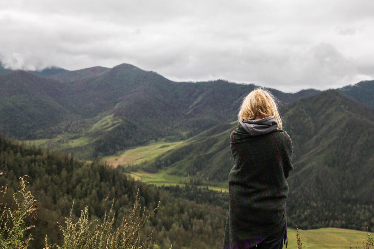 Woman in Sweater Overlooking a Mountain Range