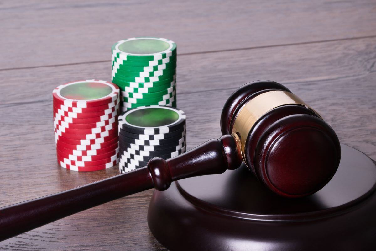 A wooden gavel and poker chips on a wooden table in a casino setting.