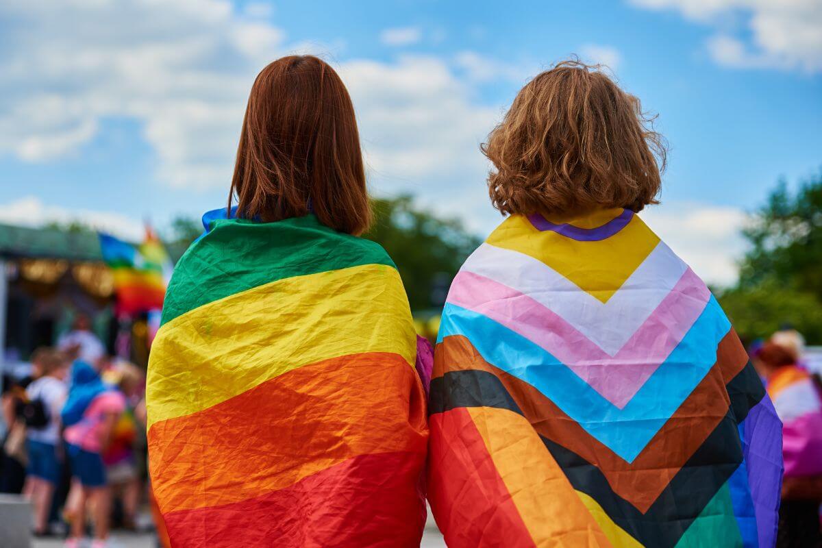 Two women with rainbow flags on their backs