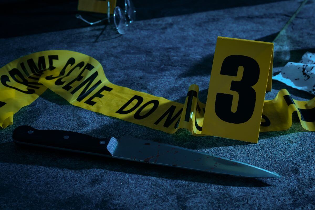 A knife on the floor next to a crime tape