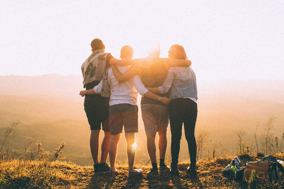 Four Friends Watching the Sunset With Their Arms Around Each Other