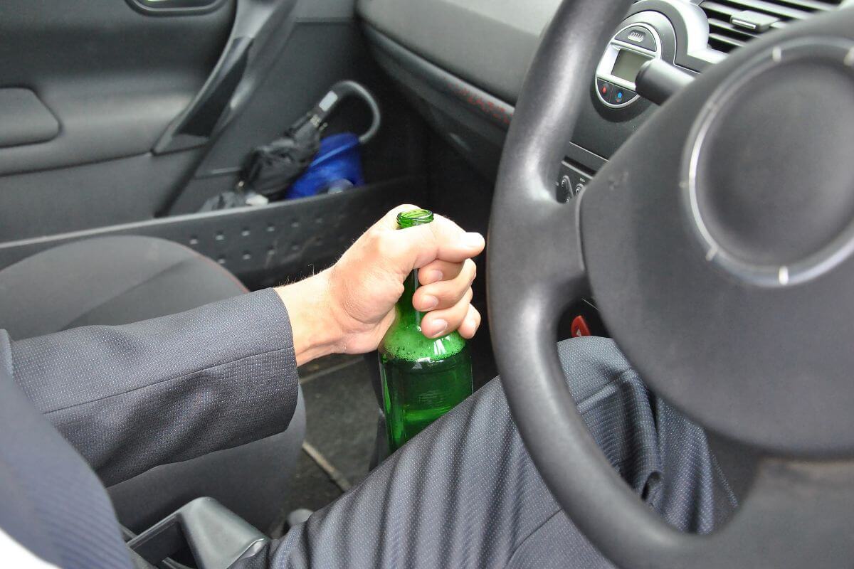 A Man and a Steering Wheel While Holding an Open Bottle of Beer in Montana