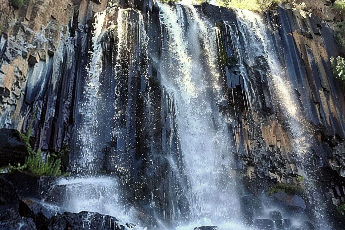 A close-up of Palisade waterfall tumbling over a cliff, featuring distinctive vertical basalt columns 