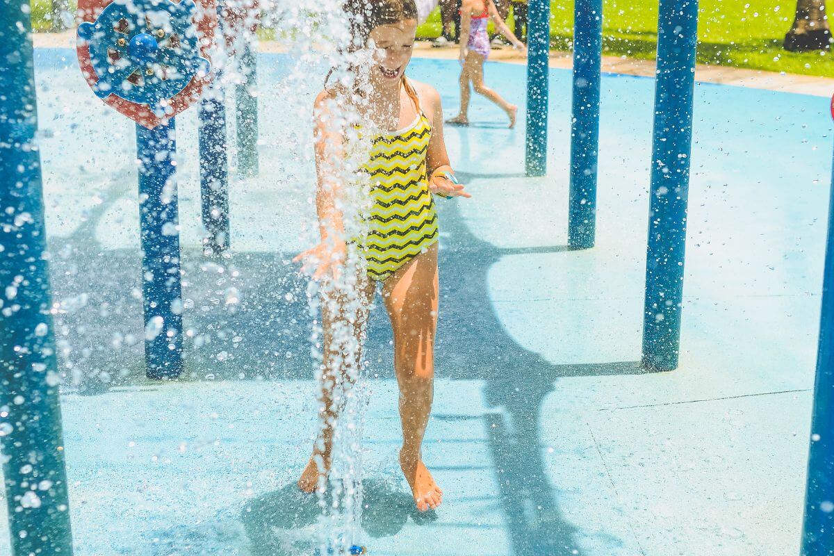 A girl enjoys one of the sprays in the Castle Rock Splash Park splash pad area from up close.