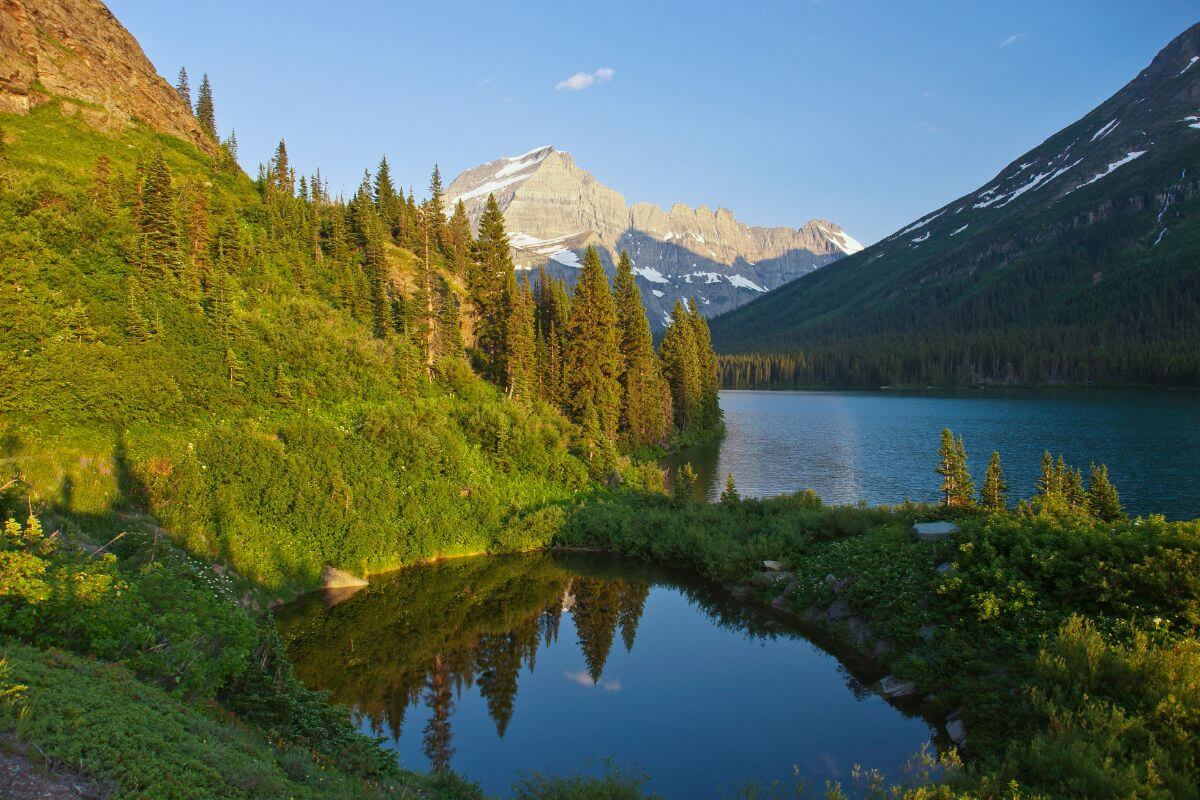 A peaceful landscape showcases Lake Josephine surrounded by lush greenery and tall mountains