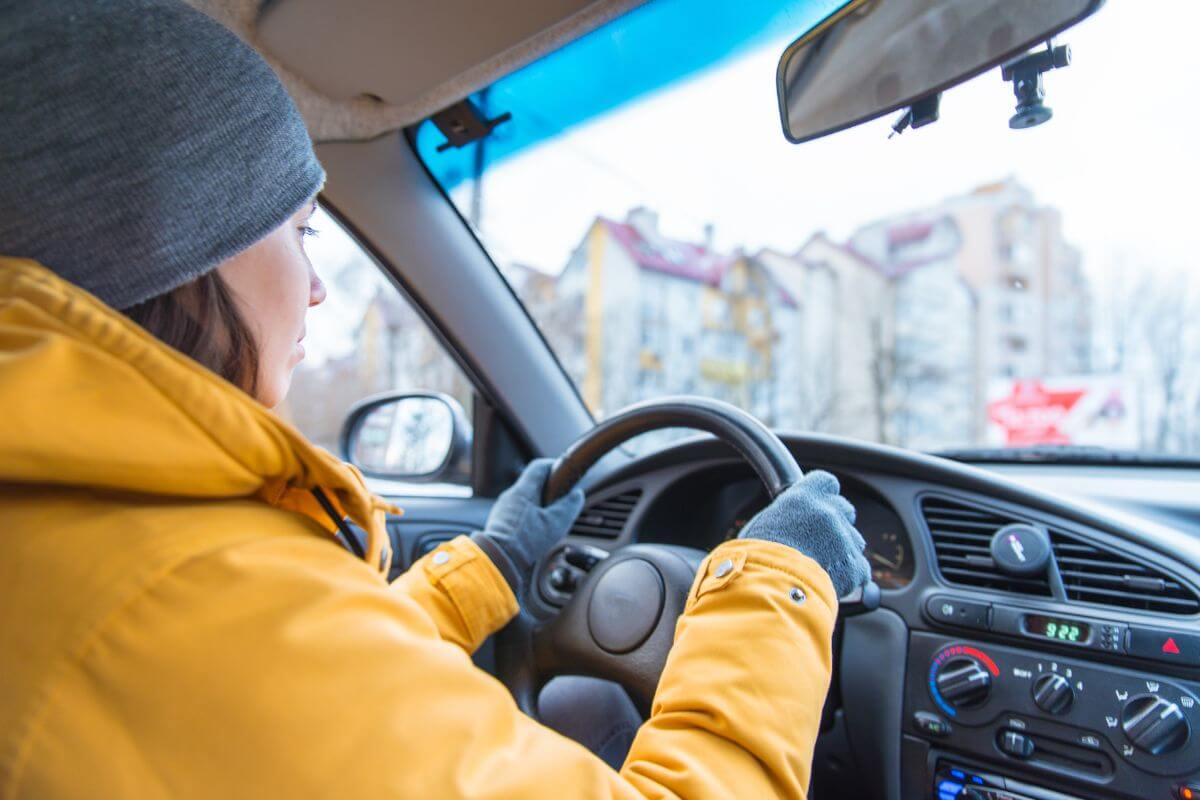 A woman is driving a car in the city during winter.