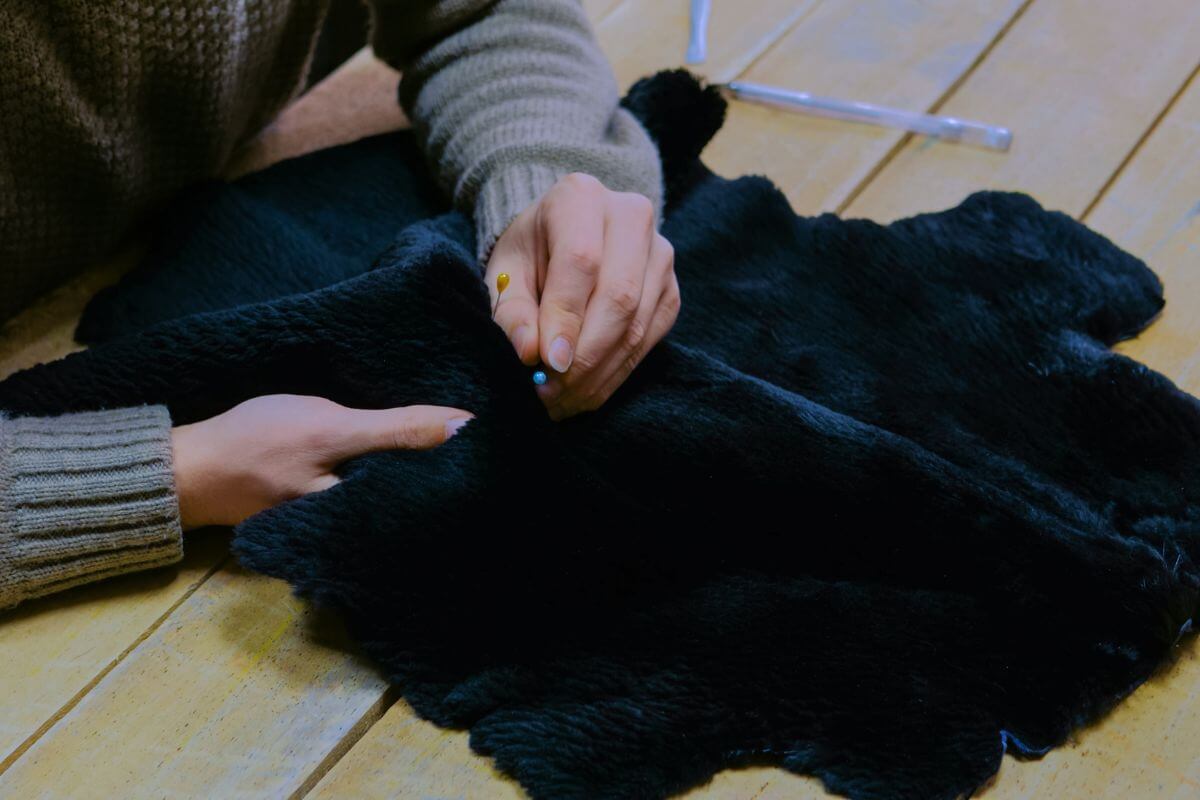 A person pinning pins onto a black sheepskin cloth on a wooden surface in Montana.