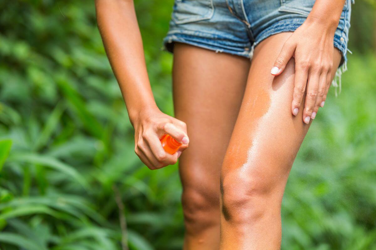 A woman in Montana is spraying bug repellent on her thigh
