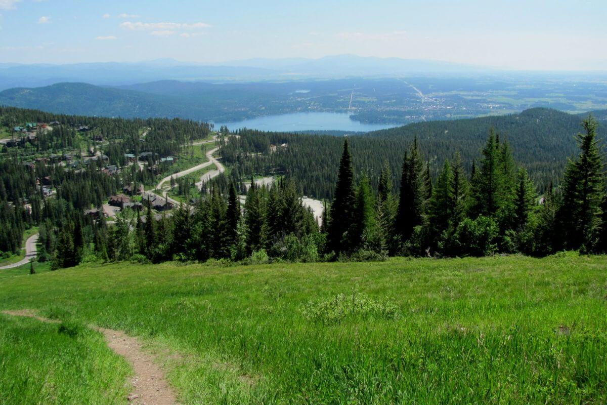 A trail leading up to a mountain with a lake in the background