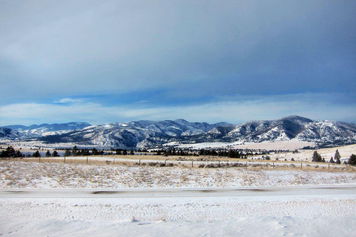 A picturesque snow-covered field in Montana with majestic mountains in the background.