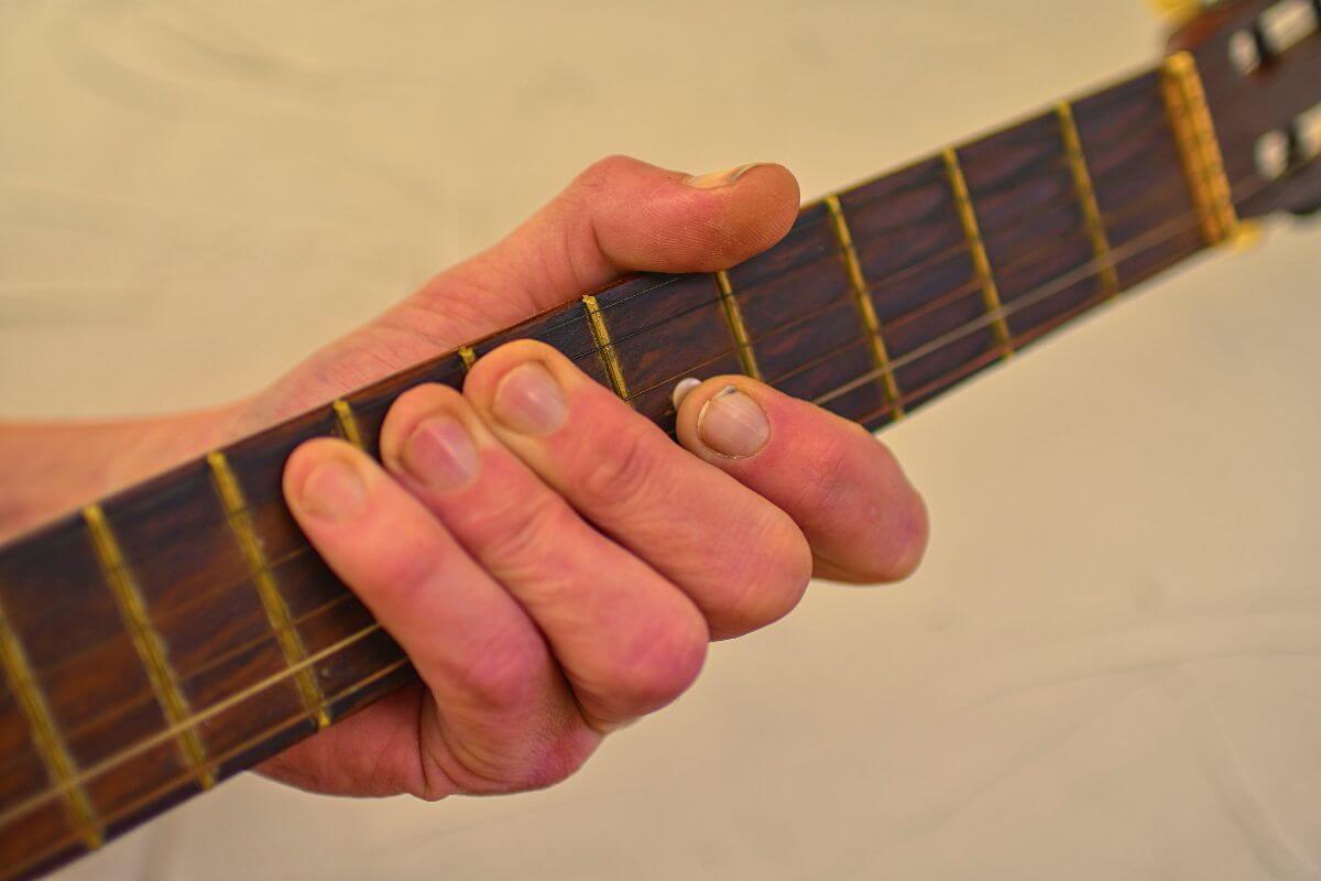 A person's hand playing an acoustic guitar.