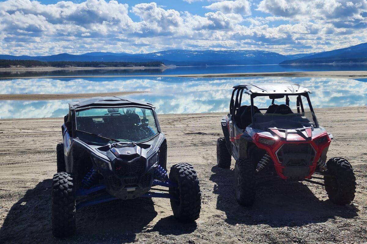 Two off-road UTV rentals from Action Rentals parked side by side on a lakeshore