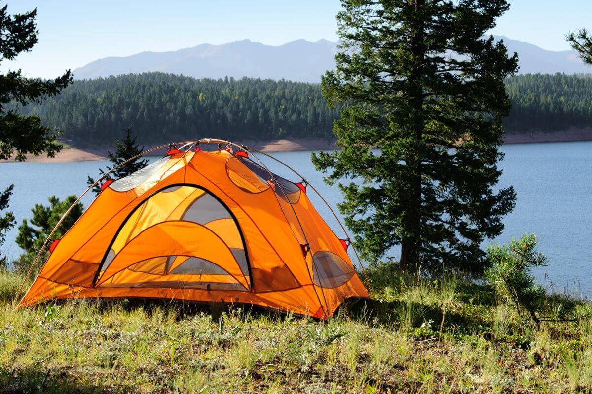 An orange tent pitched on the grassy lakeside of Holland Lake Campground 