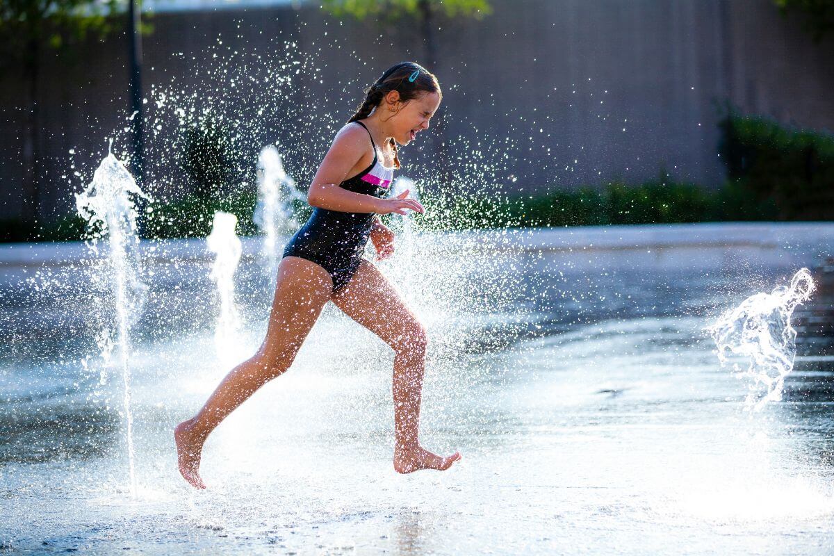 A girl runs joyfully across Castle Rock Splash Park's splash pad area