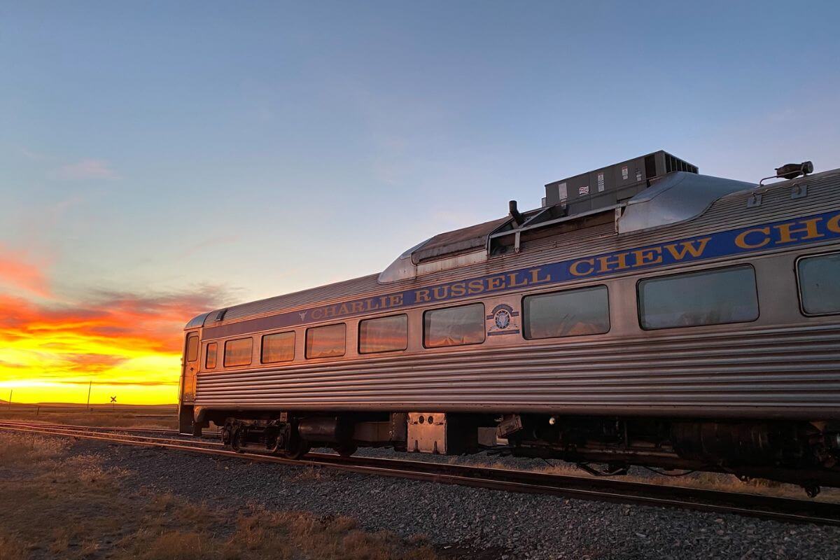 The Charlie Russell Chew-Choo Dinner Train basks in the warm glow of a sunset, one of the best Montana train tours.