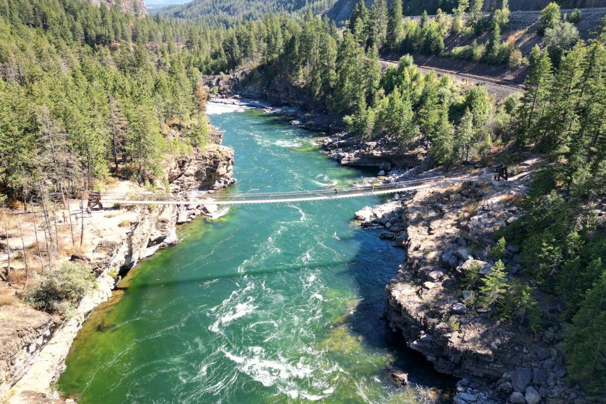 An aerial view of a suspension bridge over a river in Kootenai Falls and Swinging Bridge in Montana.