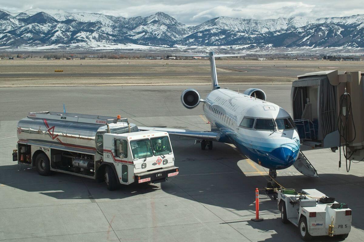 A fuel truck is approaching a plane parked on an airport runway.