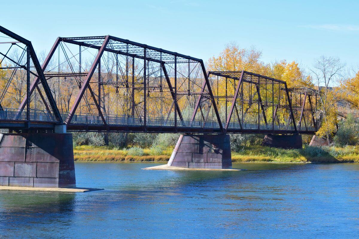 A railroad bridge over a river with trees in the background, showcasing Montana's legacy.