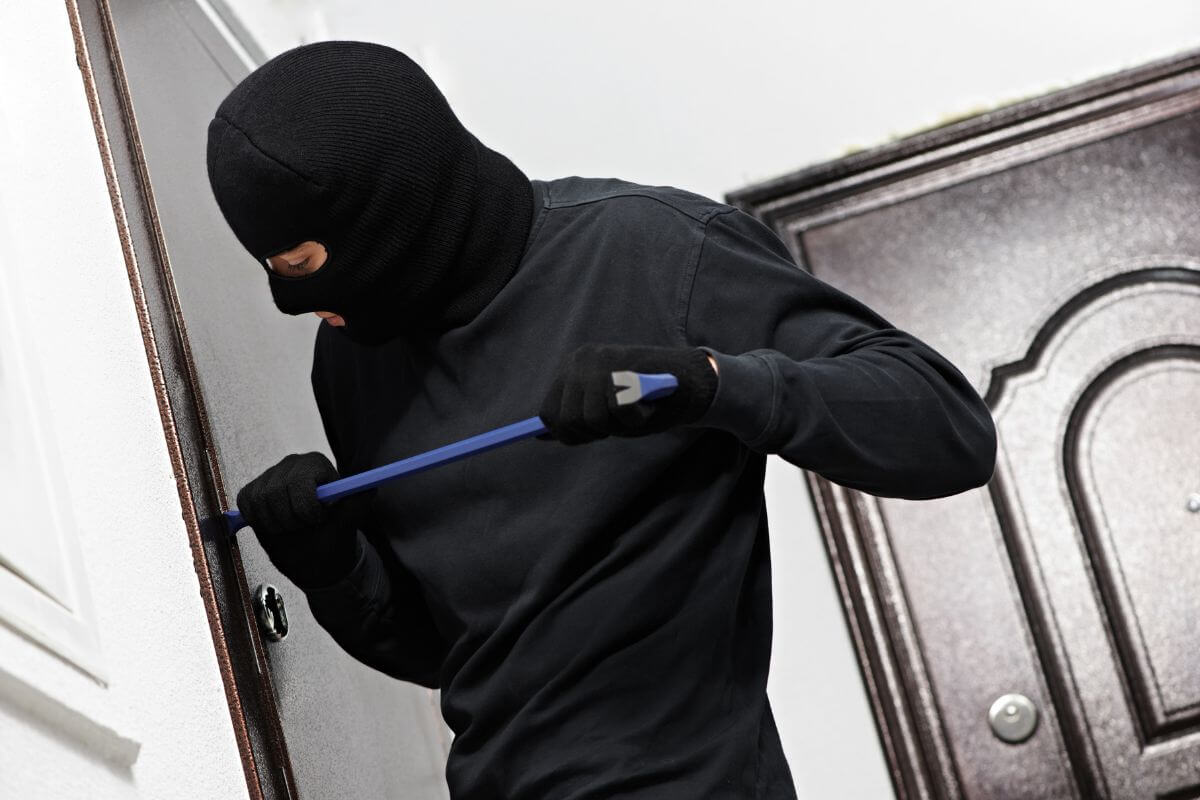 A thief in a black hoodie wielding a blue stick