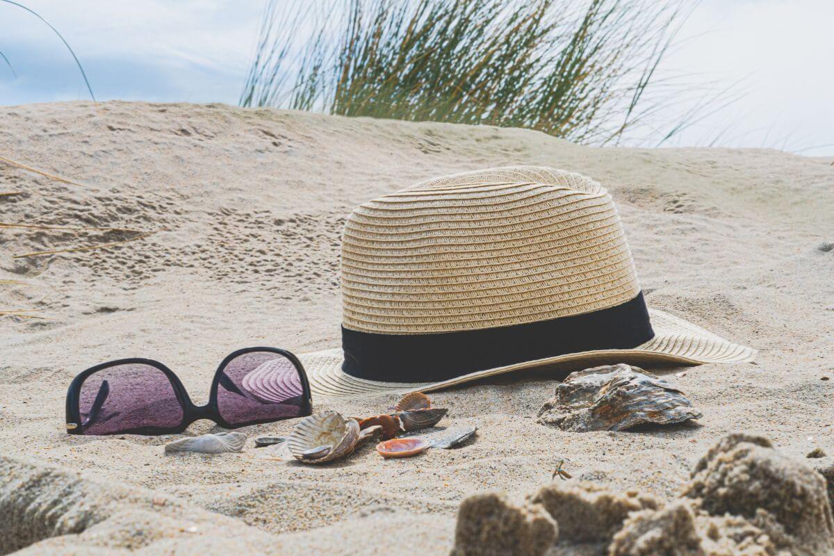 A hat, sunglasses, and shells on the sand in Montana.