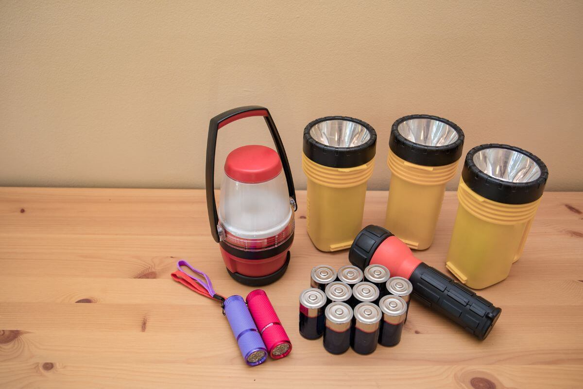 Flashlights, batteries, and a lantern on a wooden table in preparation for a Montana tornado.