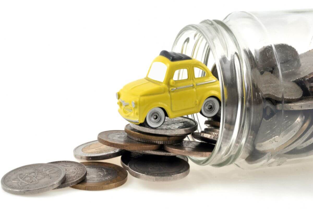 A glass jar with a yellow toy car and coins