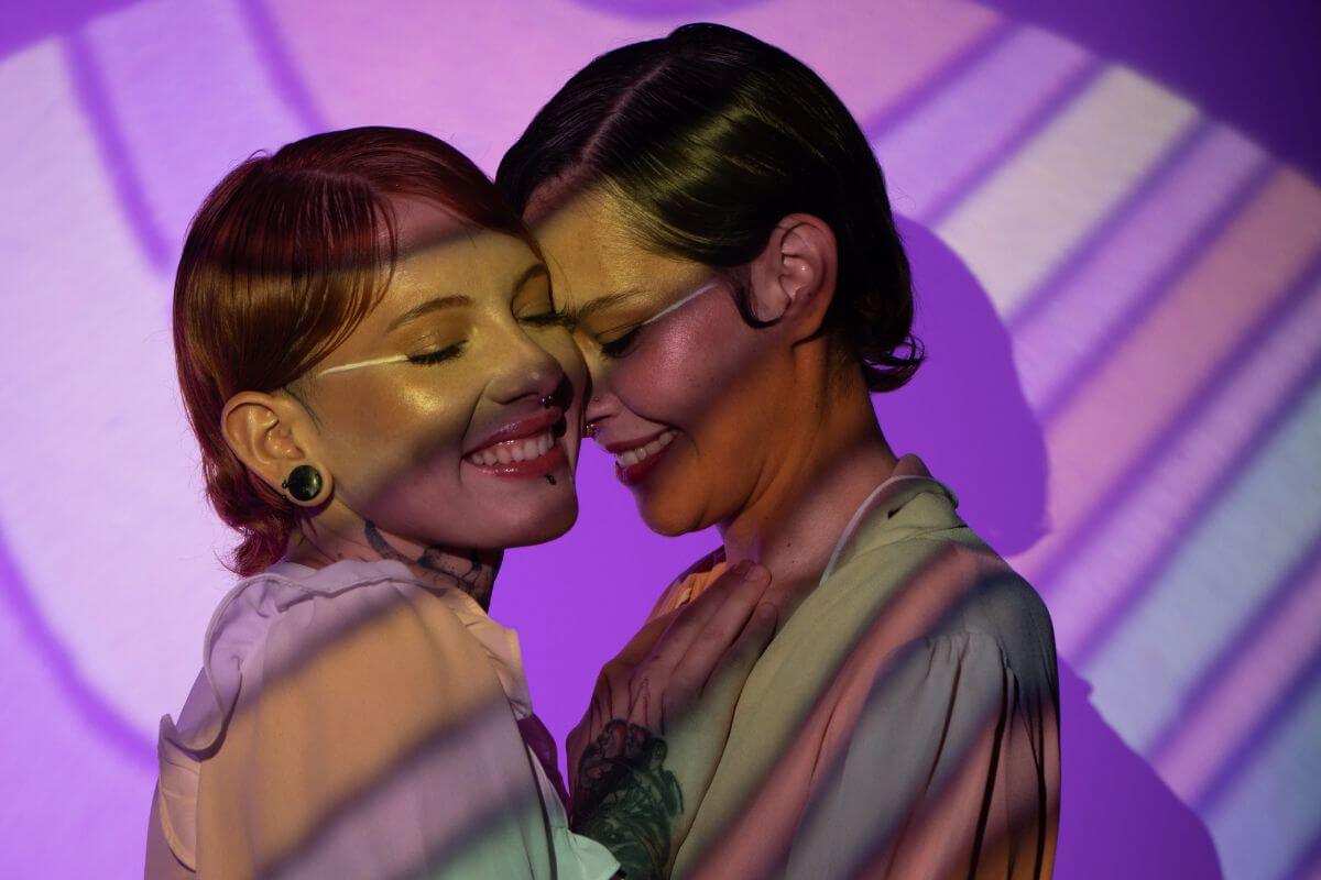 Two women hugging in front of a purple light